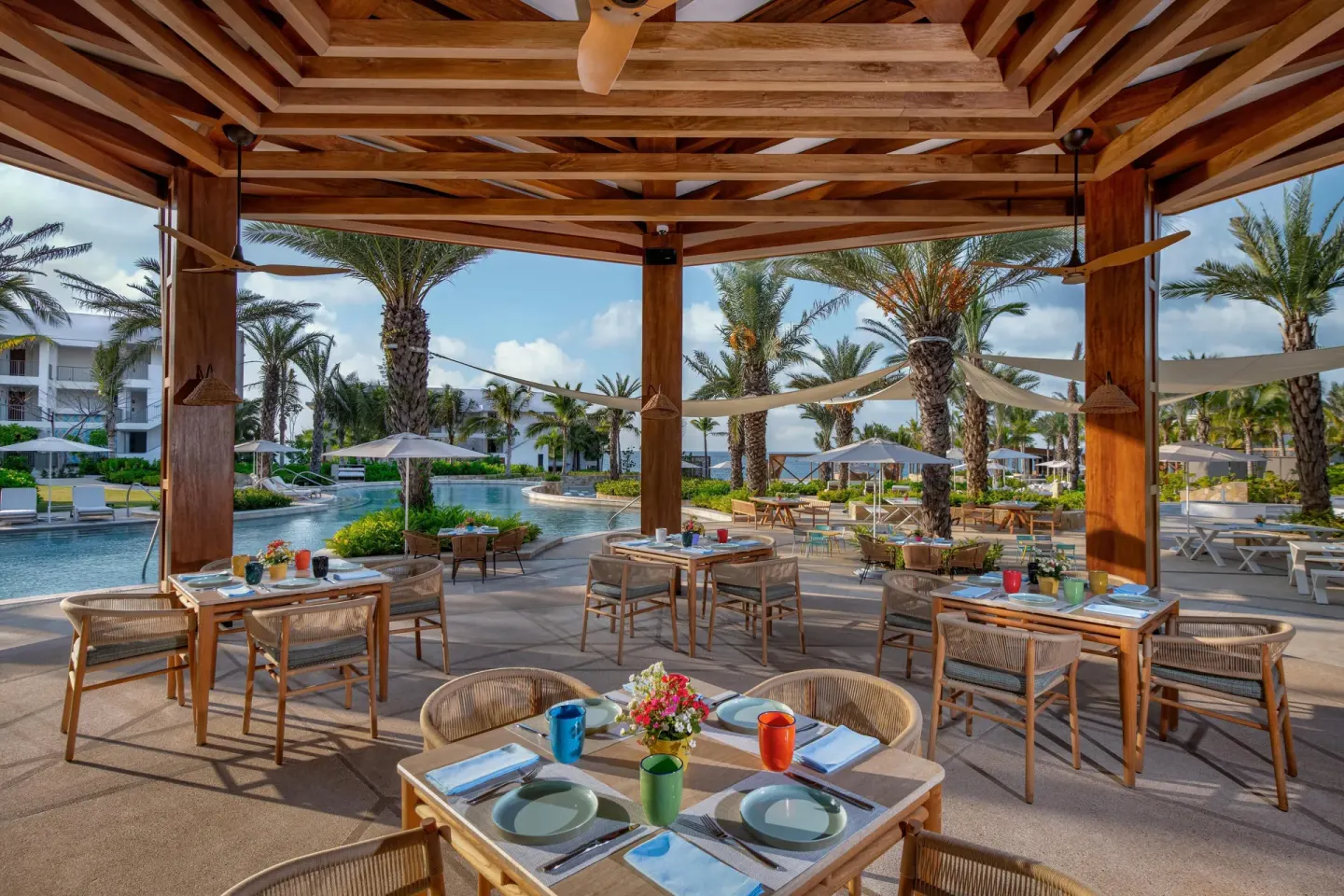 Poolside dining pavilion with set tables and palm-lined pools at Conrad Punta de Mita.