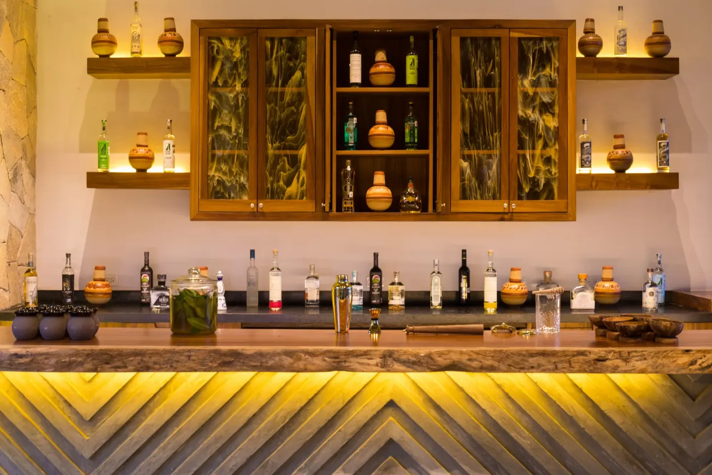 Agave spirits bar with bottles, wood shelving and a stone-front counter at Conrad Punta de Mita.