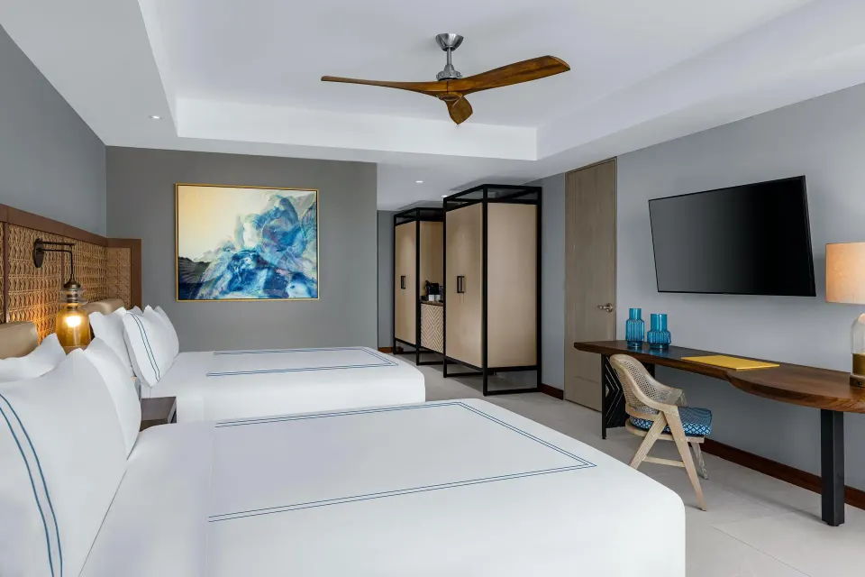 Ocean View room with two beds, desk, TV and wardrobe area at Conrad Punta de Mita.