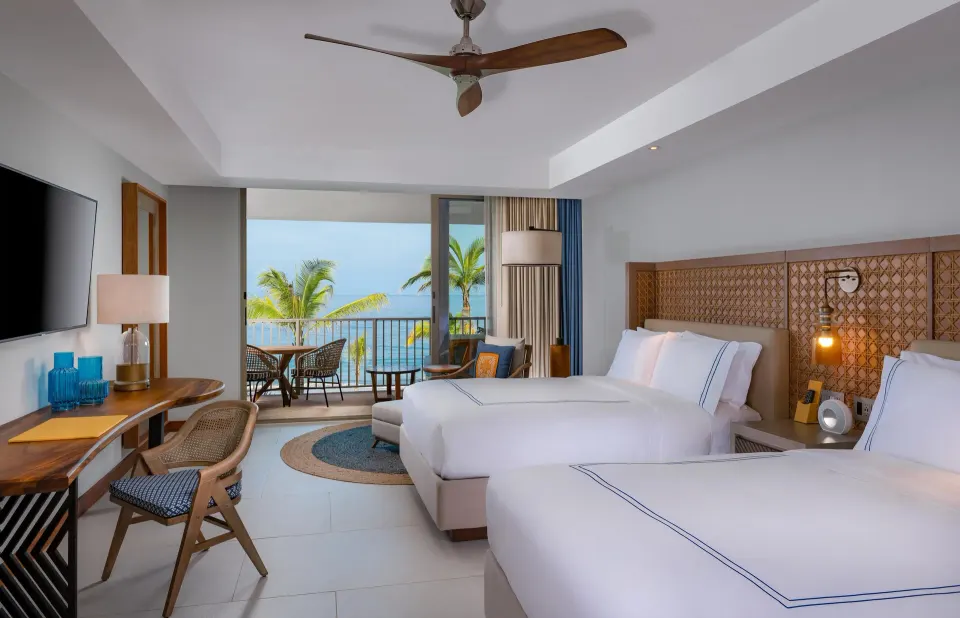 Ocean View room with two beds, balcony chairs and palm-framed ocean view at Conrad Punta de Mita.