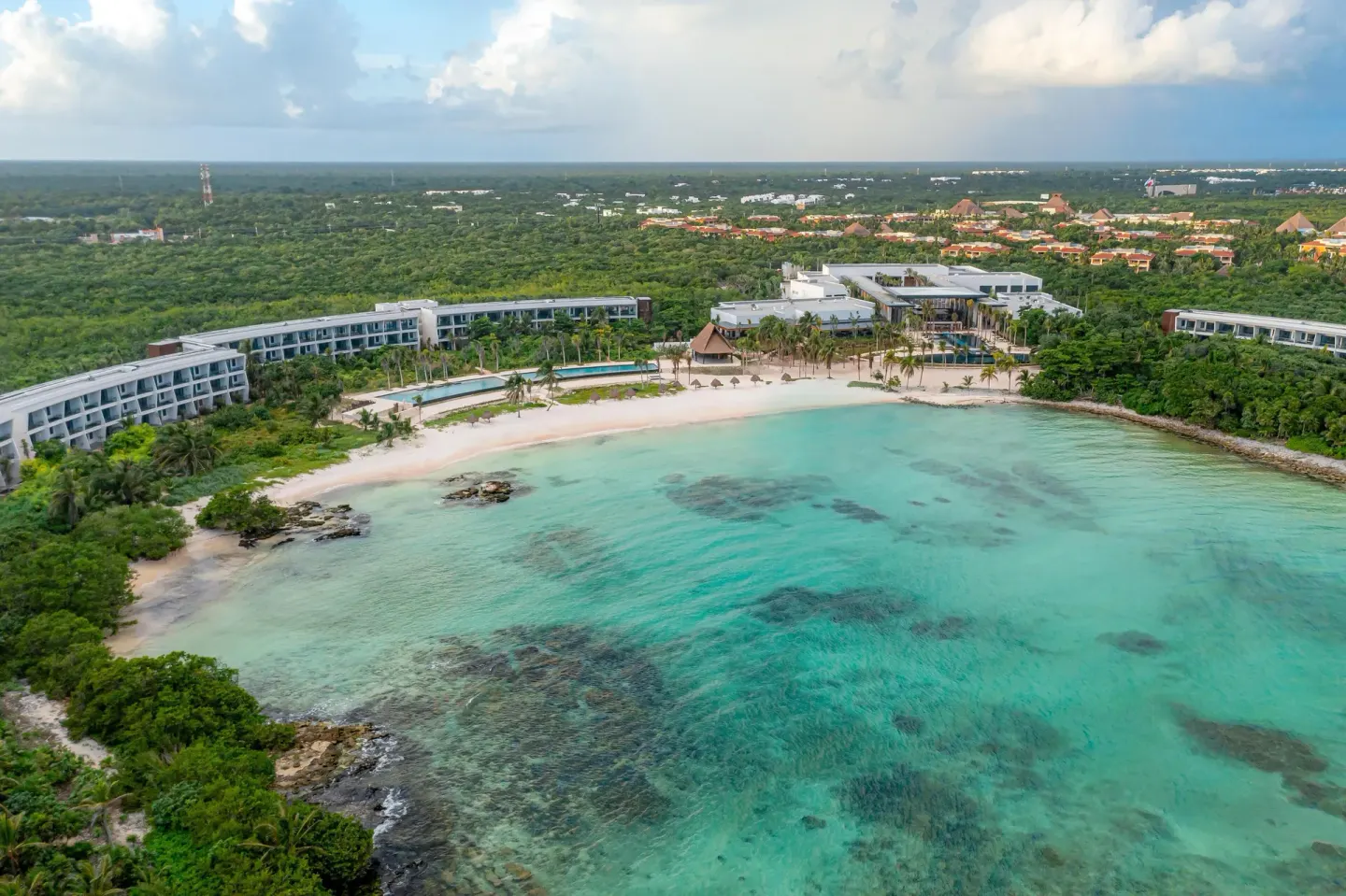 Aerial view of the beach, turquoise bay and resort buildings at Conrad Tulum Riviera Maya.