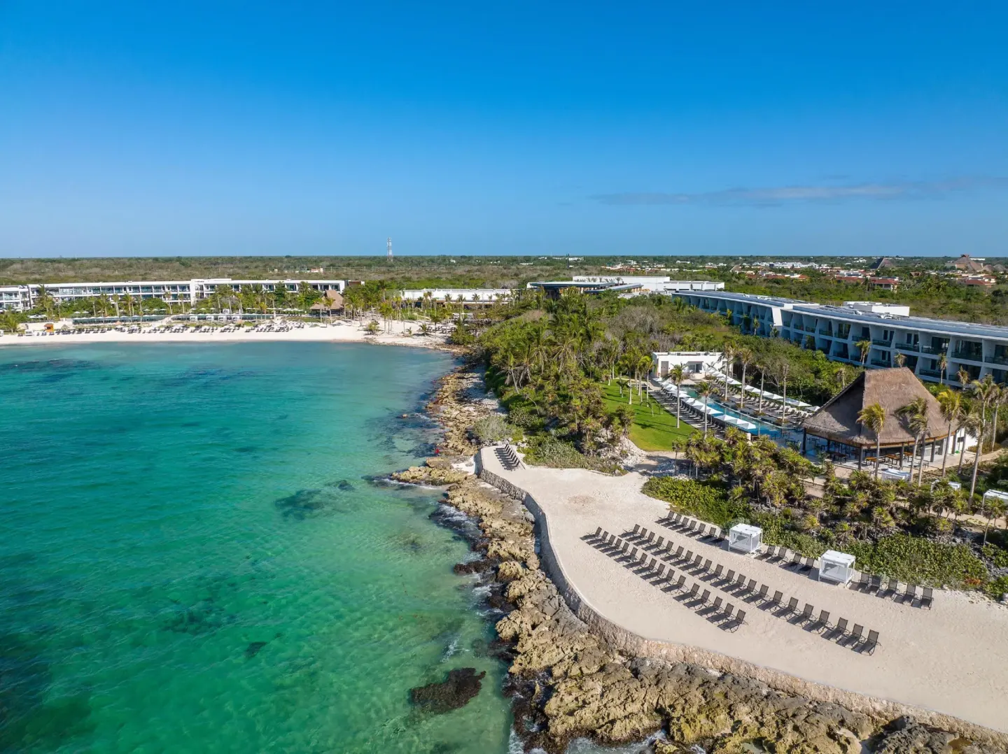 Aerial coastline view of Conrad Tulum Riviera Maya with turquoise water, beach loungers, and resort buildings.