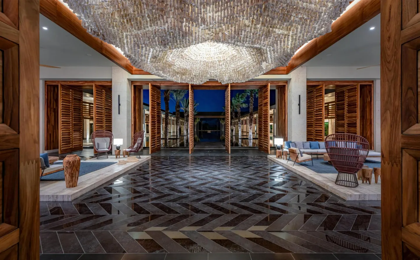 Evening lobby view with chandelier, wood shutters, and seating at Conrad Tulum Riviera Maya.