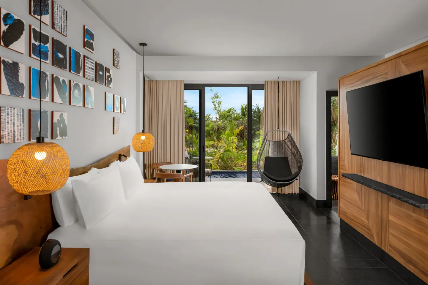 Guest room with king bed, wall art, TV, and garden-facing doors at Conrad Tulum Riviera Maya.