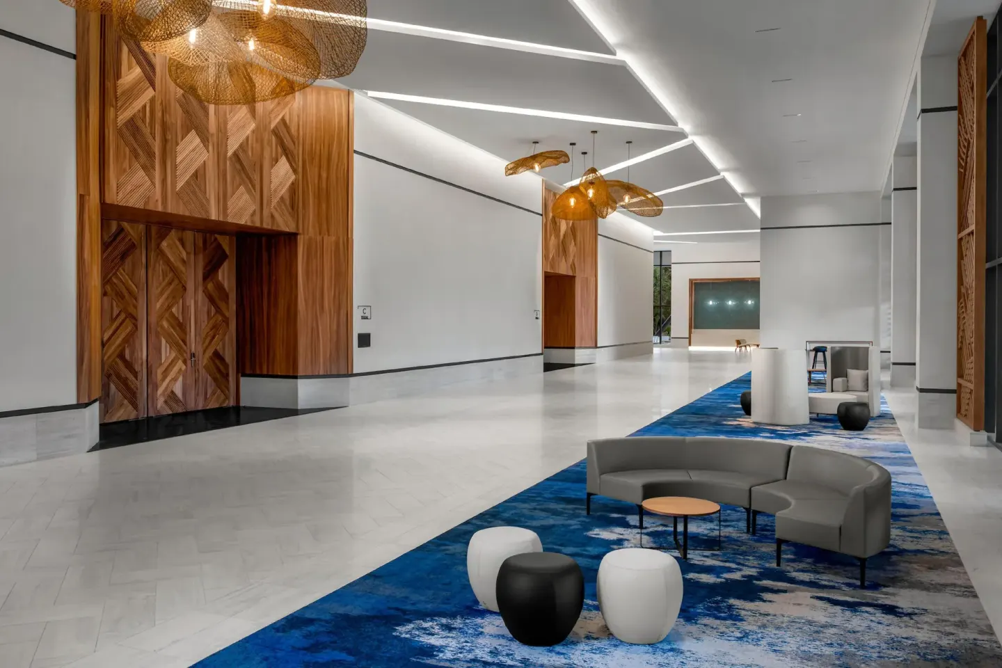 Spacious lobby corridor with blue carpet and lounge seating at Conrad Tulum Riviera Maya.