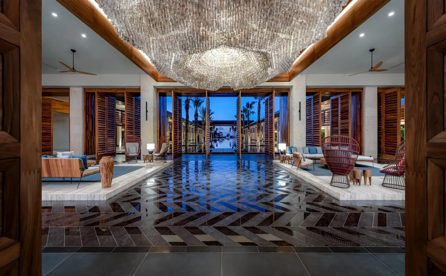 Open-air lobby with glossy floors, seating areas, and chandelier at Conrad Tulum Riviera Maya.