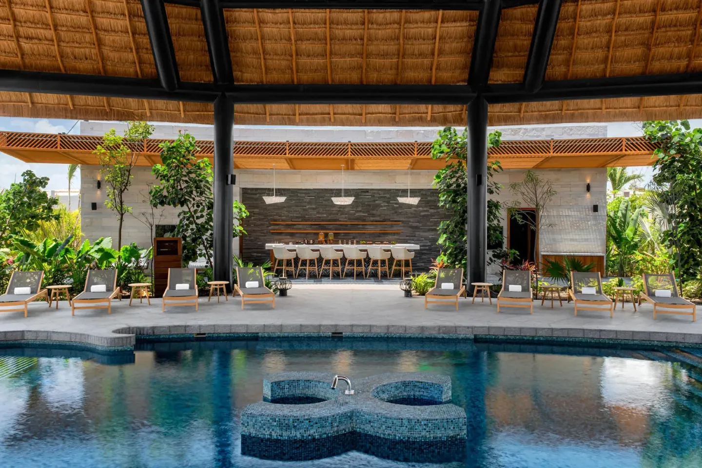 Poolside loungers and bar at Conrad Tulum Riviera Maya.