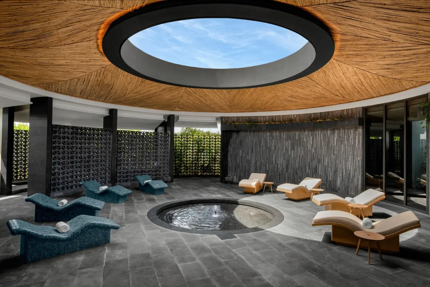 Spa lounge with chaise seating around a round water feature at Conrad Tulum Riviera Maya.