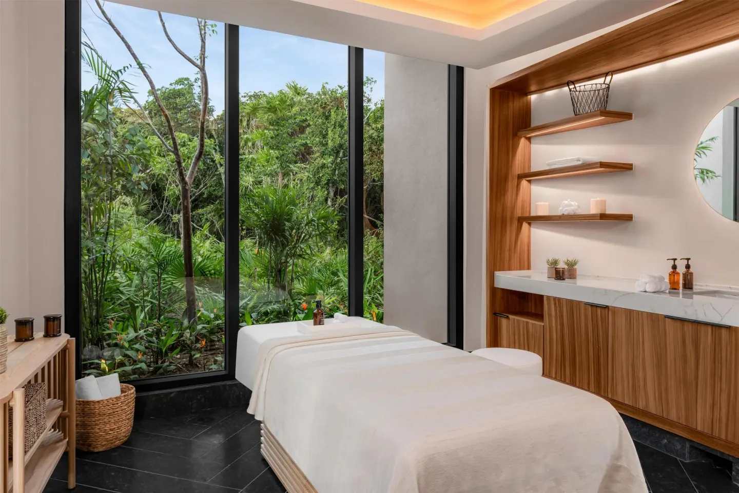 Spa treatment room with a massage bed and jungle-facing windows at Conrad Tulum Riviera Maya.