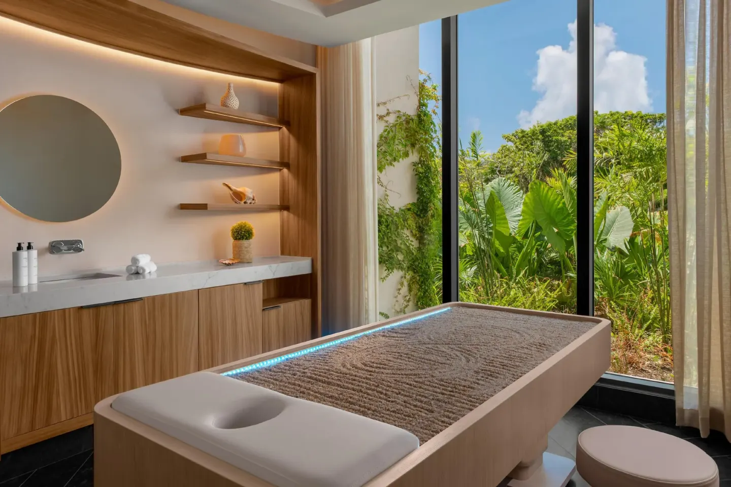 Spa treatment room with massage table and garden windows at Conrad Tulum Riviera Maya.
