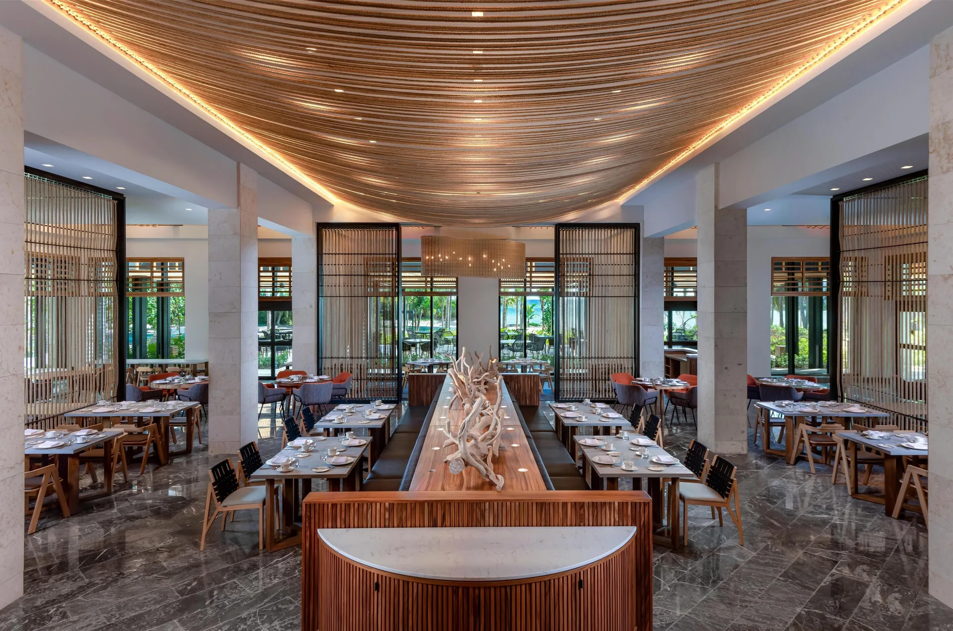 Elegant restaurant dining room with set tables and curved wood ceiling at Conrad Tulum Riviera Maya.