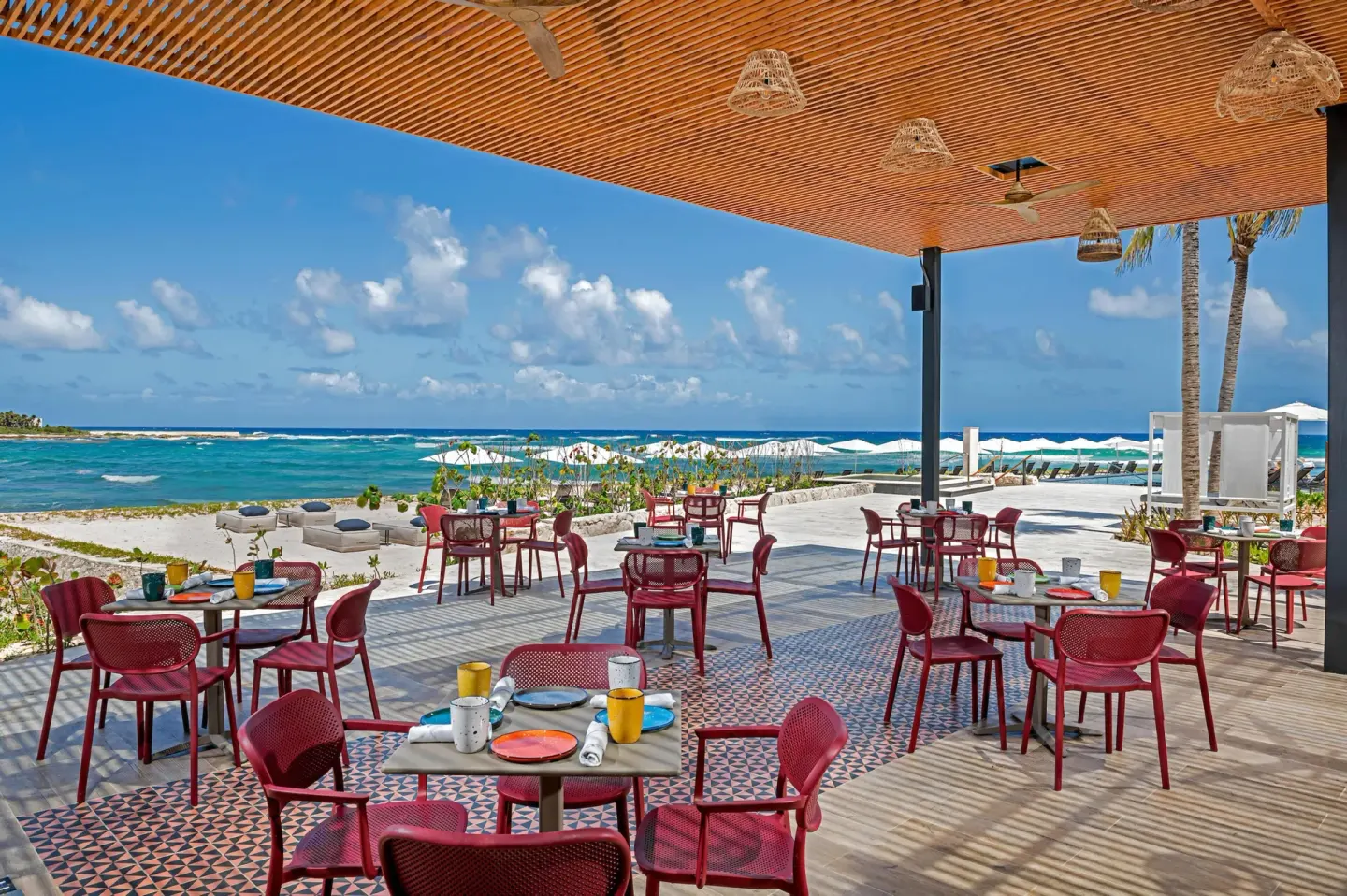 Beachfront terrace with red dining chairs and ocean views at Conrad Tulum Riviera Maya.