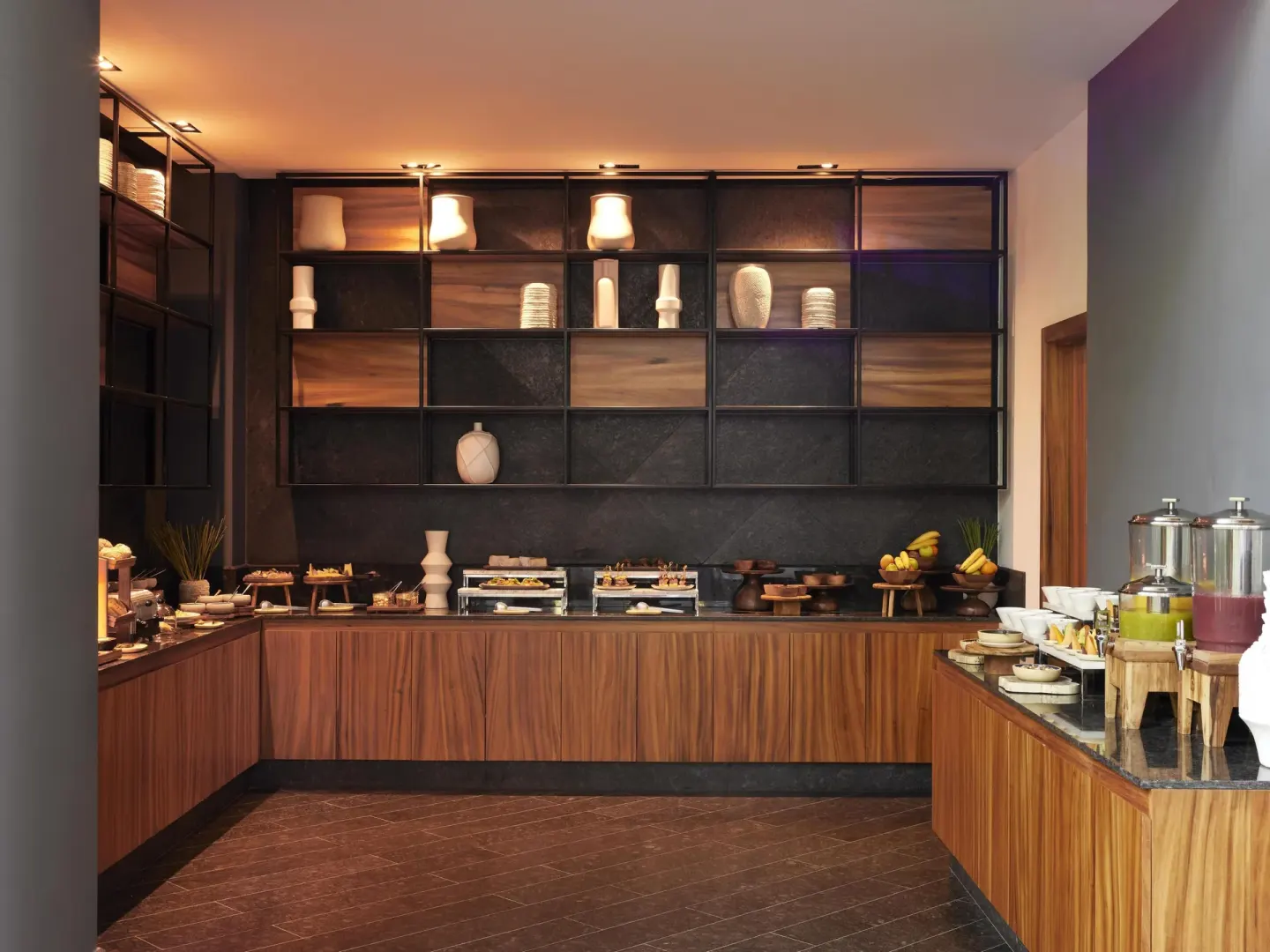 Wood-paneled buffet alcove with pastries, fruit, and beverage dispensers at Conrad Tulum Riviera Maya.