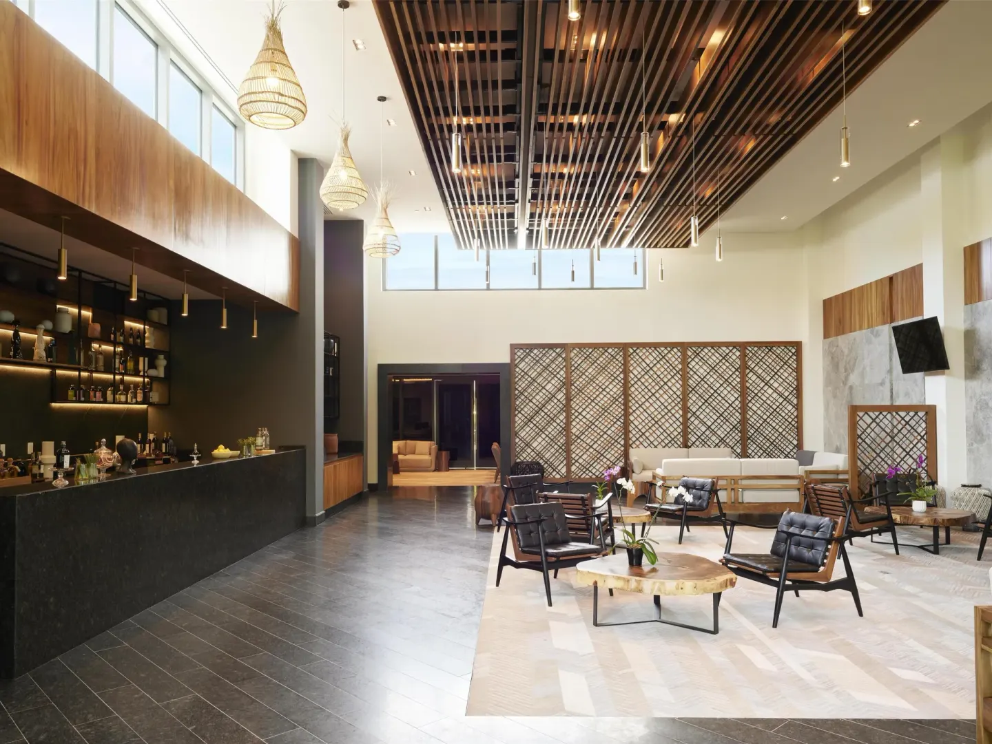 Open lobby lounge with bar and woven pendant lights at Conrad Tulum Riviera Maya.