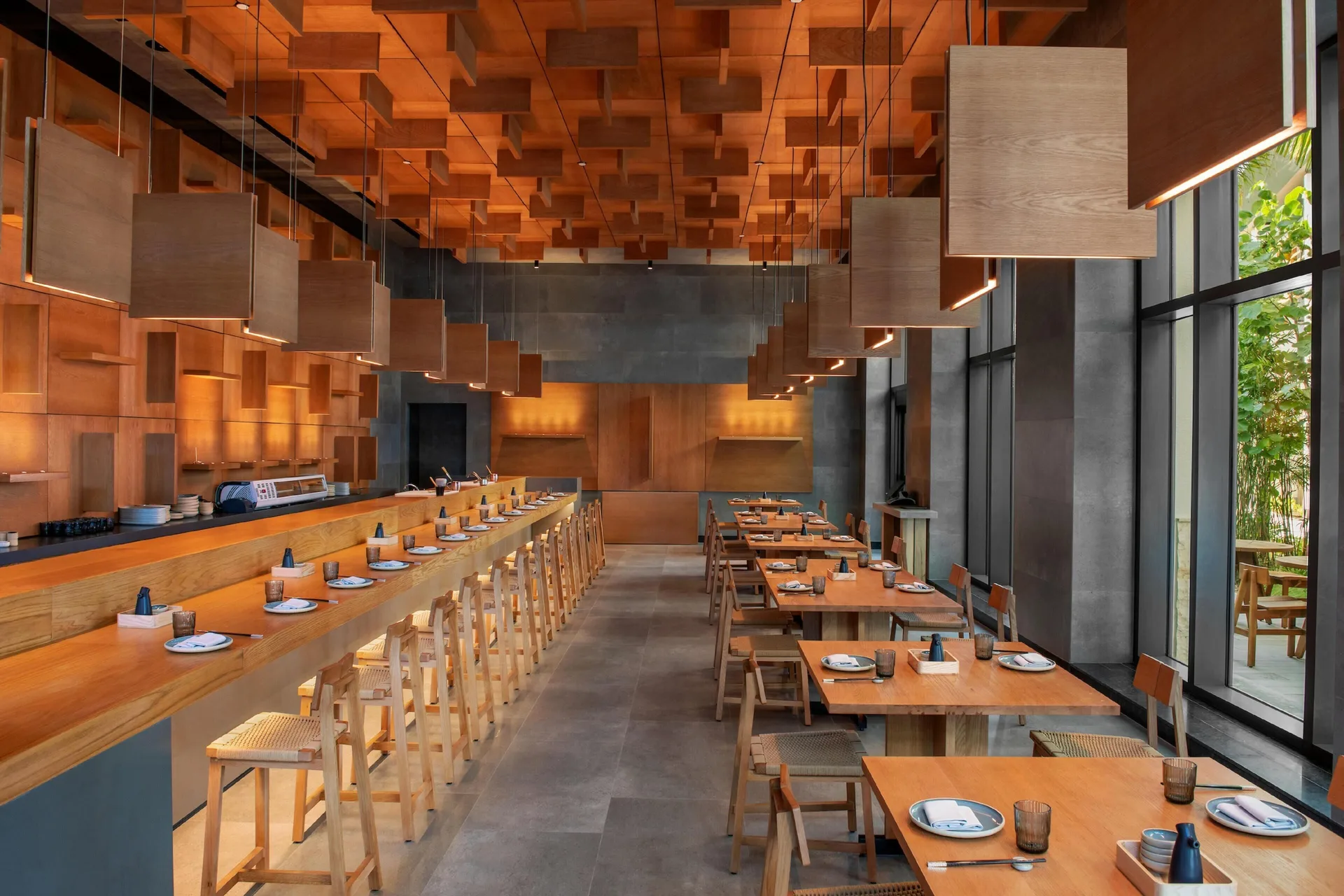 Wood-lined sushi counter and dining tables at Conrad Tulum Riviera Maya.