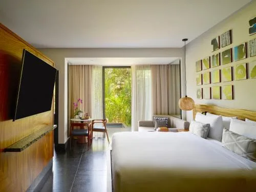 Accessible king room with wall art and garden-facing doors at Conrad Tulum Riviera Maya.