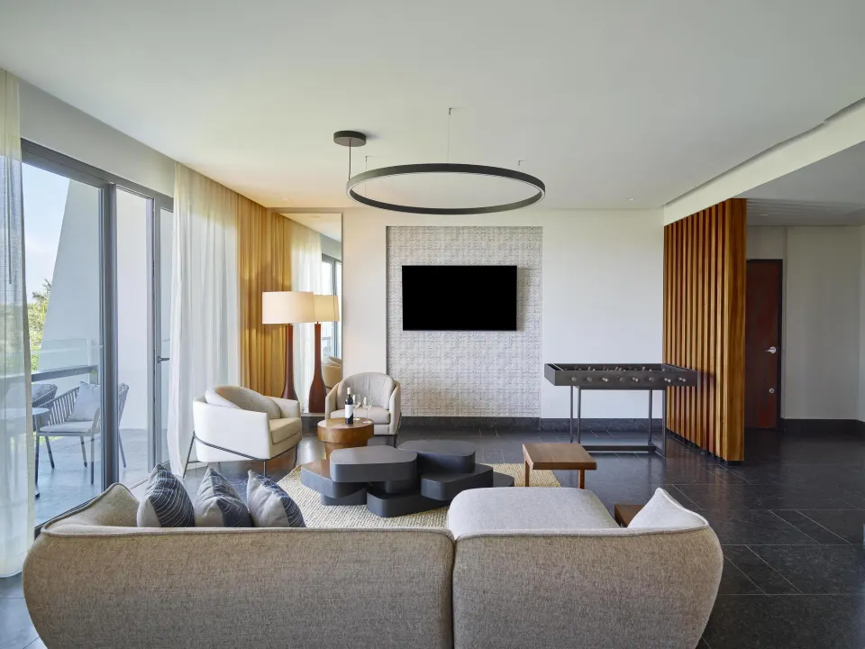 Ceiba Governors Suite living room with sofa, TV and foosball table at Conrad Tulum Riviera Maya.