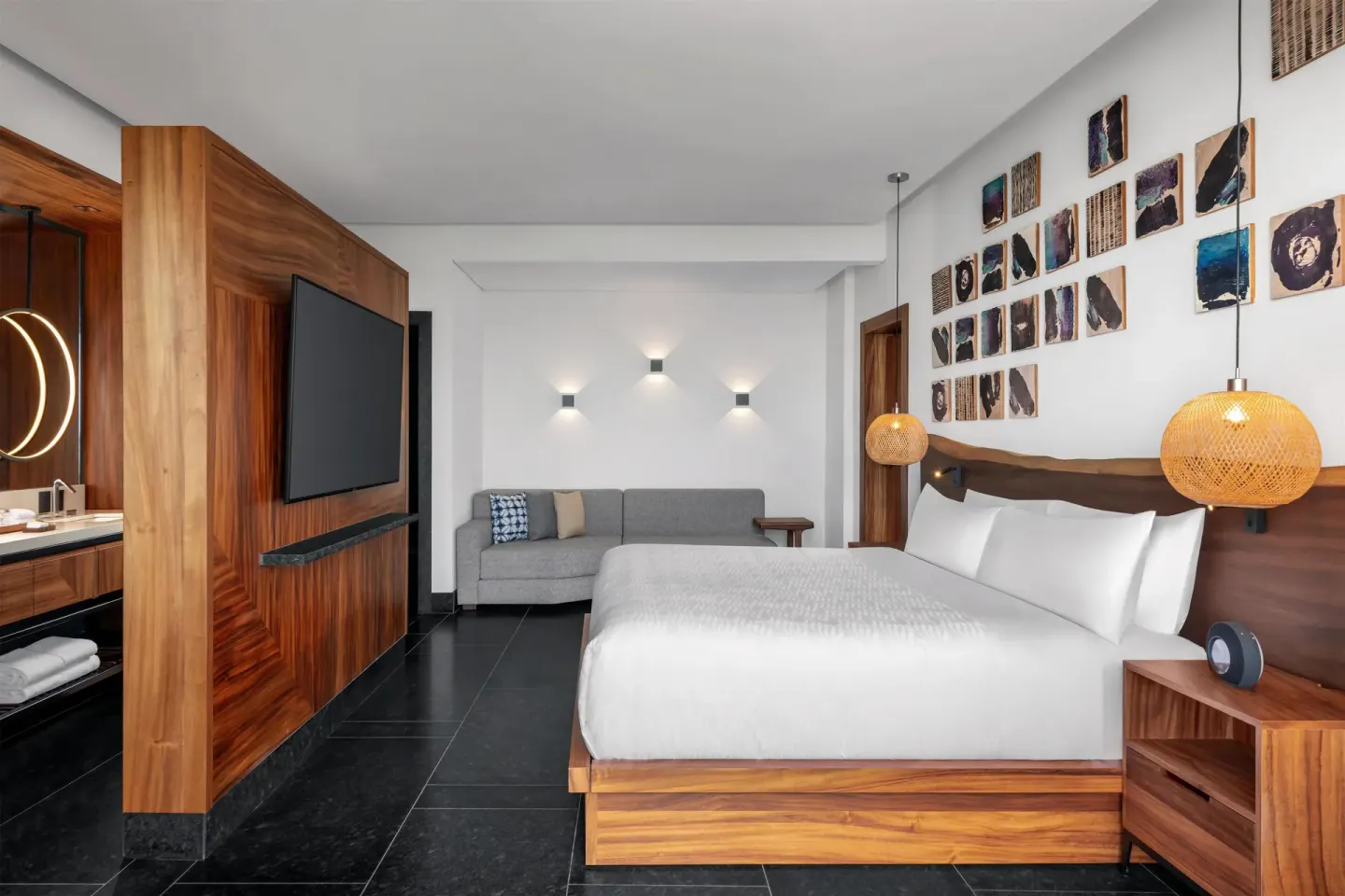 Partial Ocean View Guestroom king bed, sofa, and media wall at Conrad Tulum Riviera Maya.