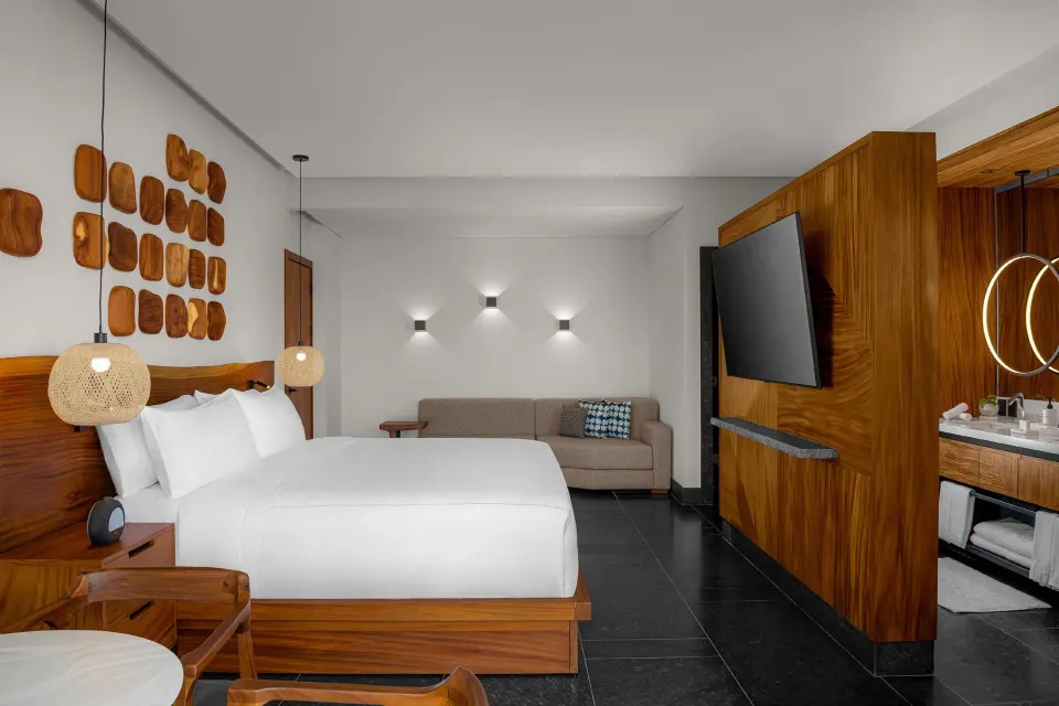 Partial Ocean View Guestroom king bed with sofa and vanity at Conrad Tulum Riviera Maya.