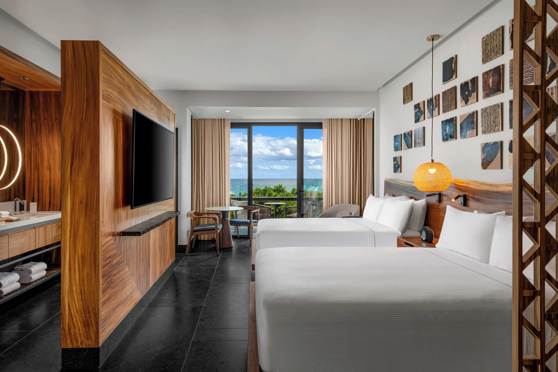 Two-bed partial ocean view guest room at Conrad Tulum Riviera Maya with balcony and seating area.