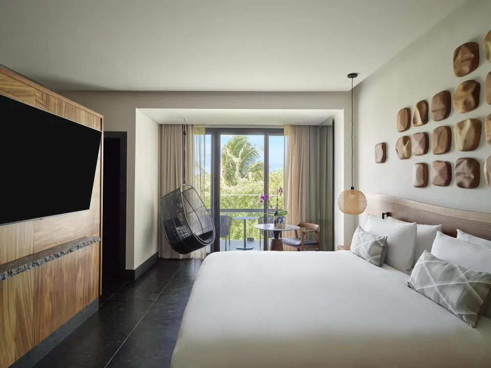 Ceiba Tropical View suite king bed with balcony and hanging chair at Conrad Tulum Riviera Maya
