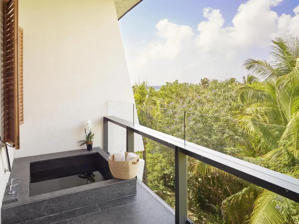 Tropical View Guestroom balcony at Conrad Tulum Riviera Maya with soaking tub and treetop view.