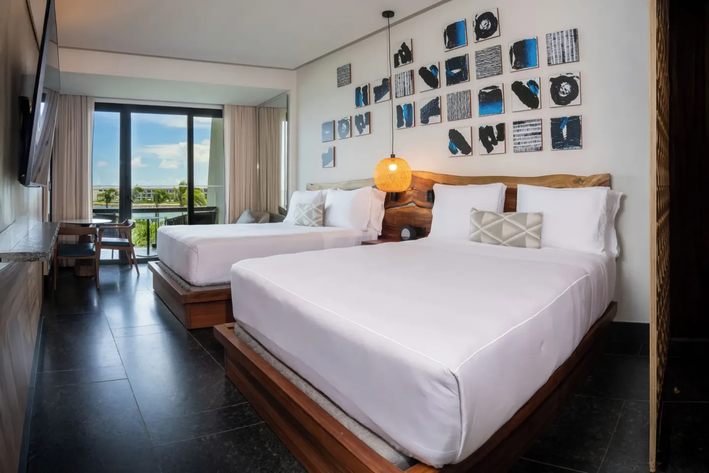 Two-bed Tropical View Guestroom at Conrad Tulum Riviera Maya with balcony doors and greenery beyond.