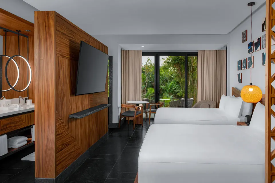 Two-bed Tropical View Guestroom at Conrad Tulum Riviera Maya with TV wall, vanity, and garden view.