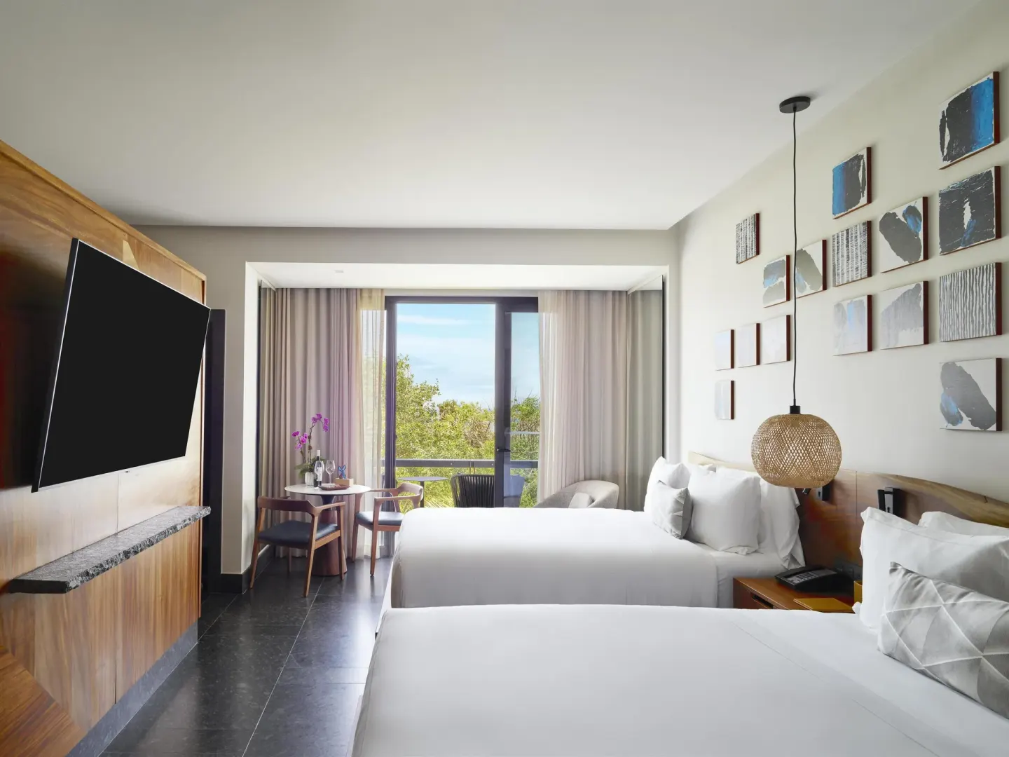 Two-bed Tropical View Guestroom at Conrad Tulum Riviera Maya with TV, balcony, and treetop view.