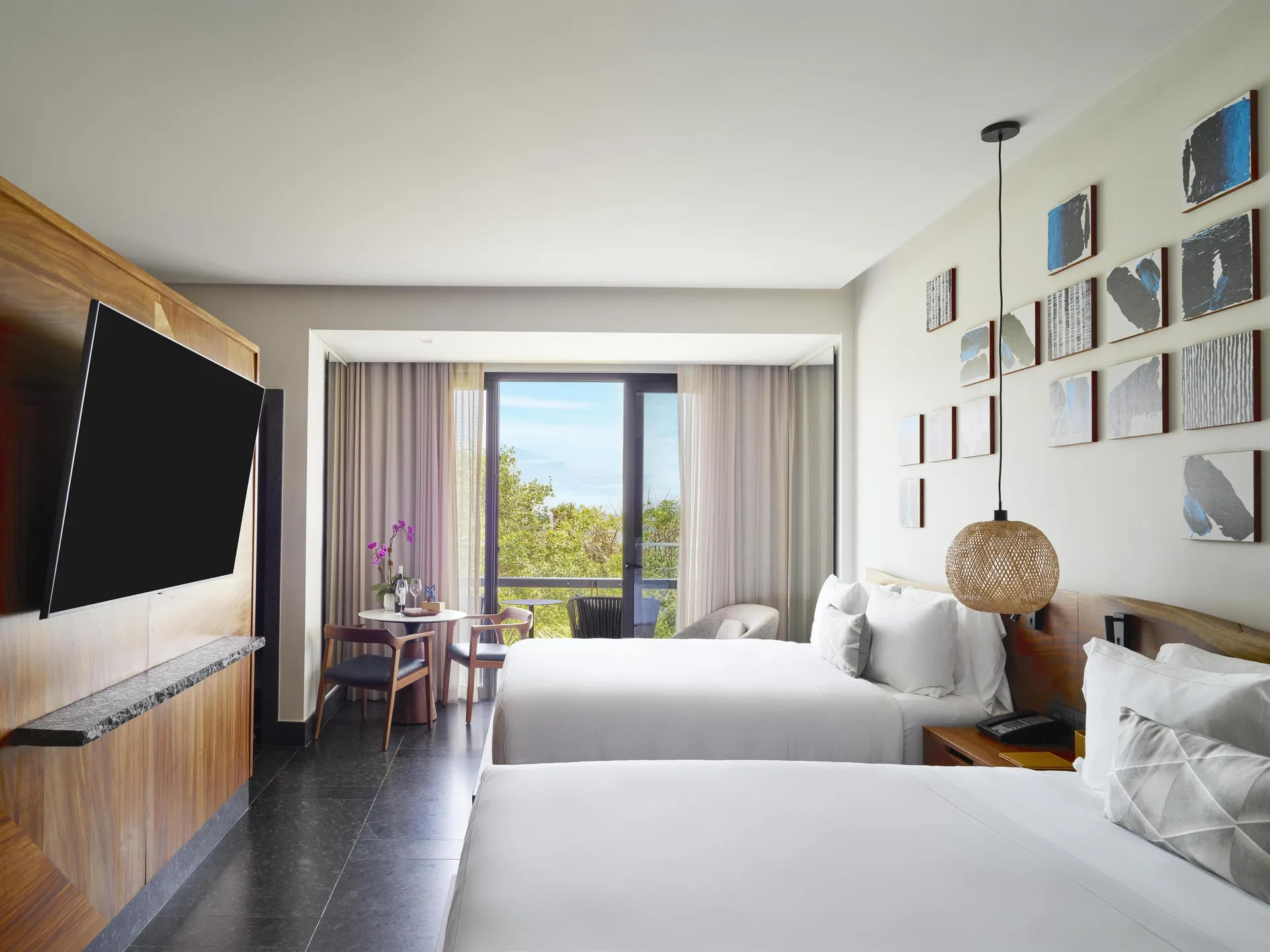 Two-bed Tropical View Guestroom at Conrad Tulum Riviera Maya with TV, balcony, and treetop view.