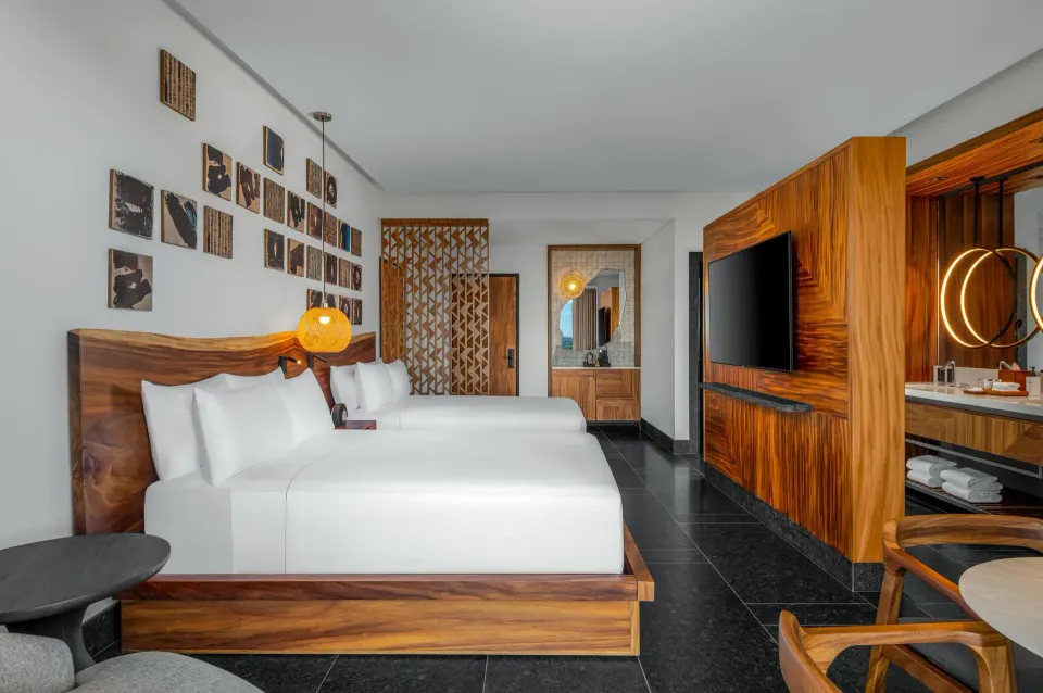 Tropical View Guestroom at Conrad Tulum Riviera Maya with two beds, TV wall, and open vanity area.