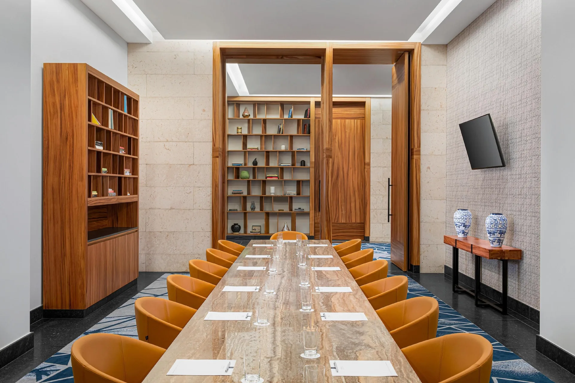 Boardroom with long marble table and orange chairs at Conrad Tulum Riviera Maya.