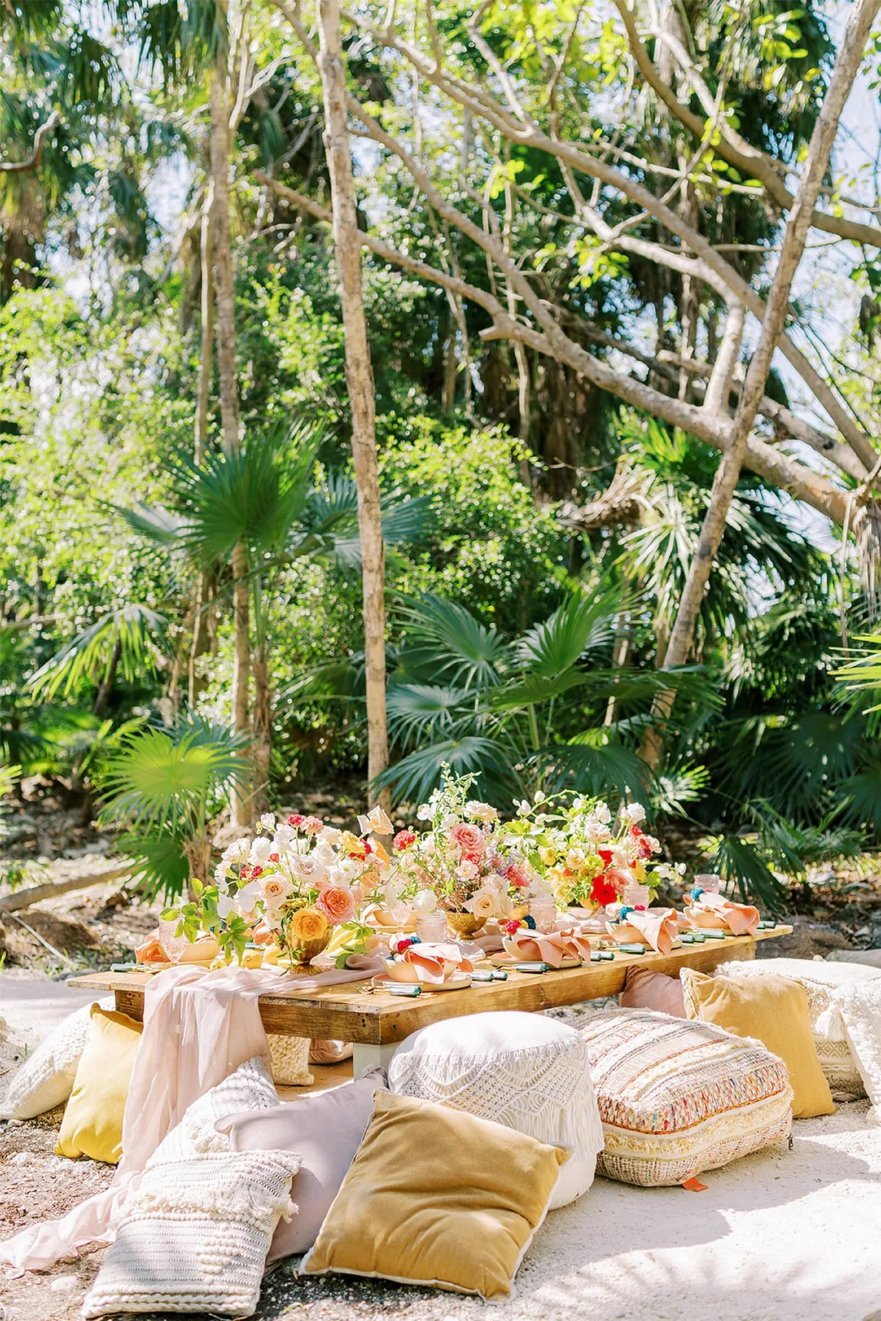 Outdoor picnic table with flowers and floor cushions at Conrad Tulum Riviera Maya.