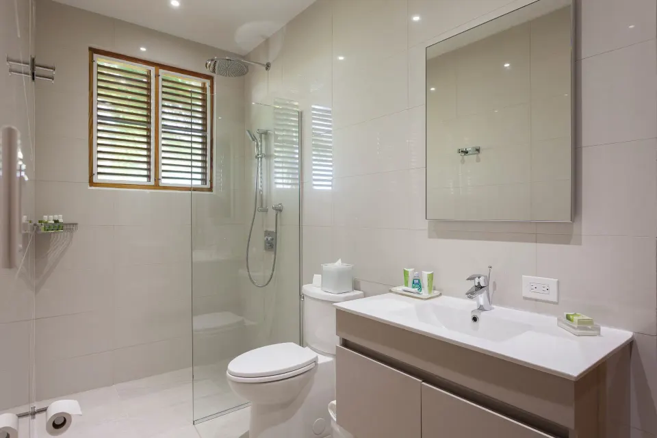 Bright bathroom with glass shower and shuttered window at Copamarina Beach Resort & Spa.