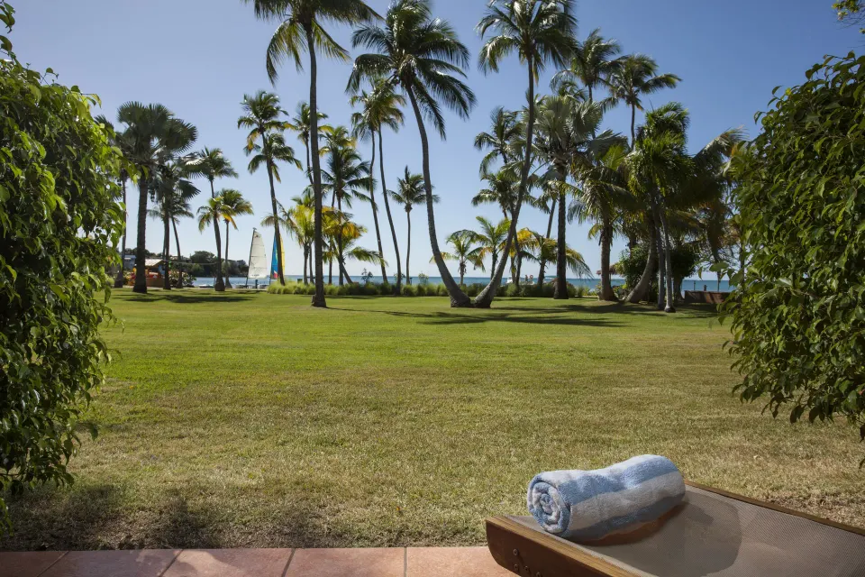 Lawn terrace with a rolled towel facing palms and water at Copamarina Beach Resort & Spa.