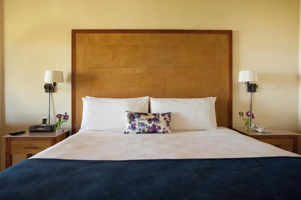 King bed with wood headboard and bedside lamps at Copamarina Beach Resort & Spa.