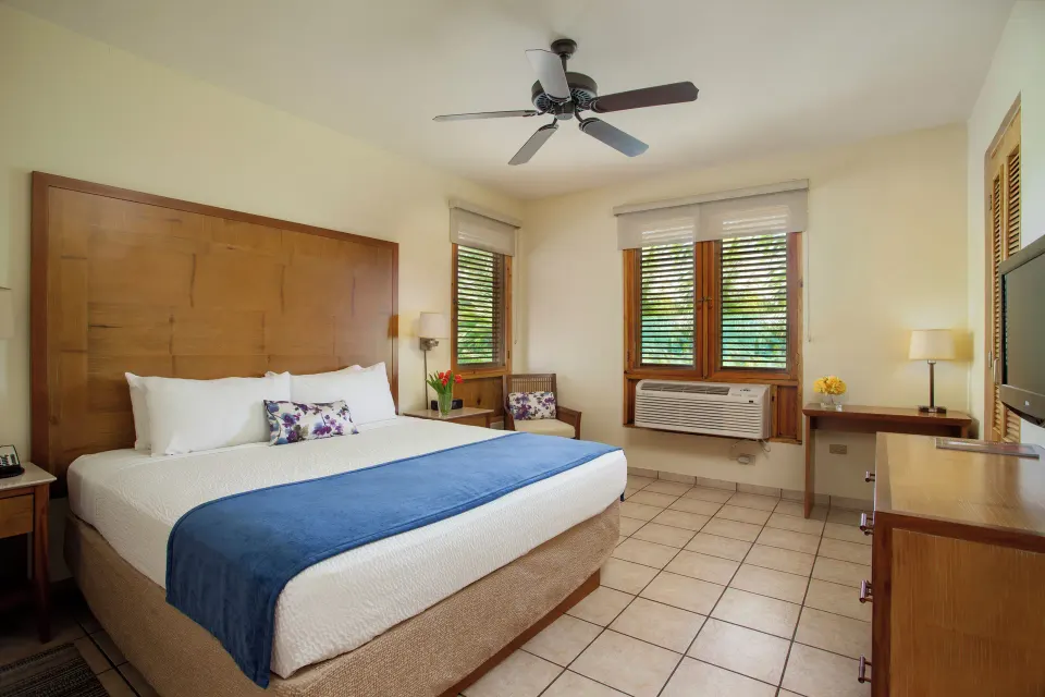 Guest room with king bed and shuttered windows at Copamarina Beach Resort & Spa.