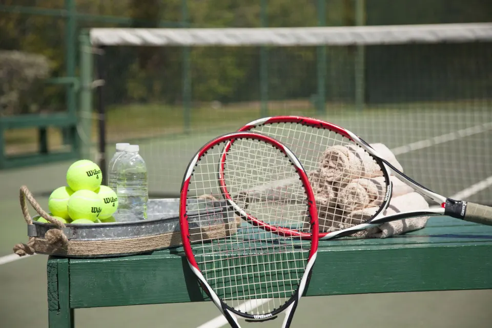 Tennis rackets, balls, and water on a court at Copamarina Beach Resort & Spa.