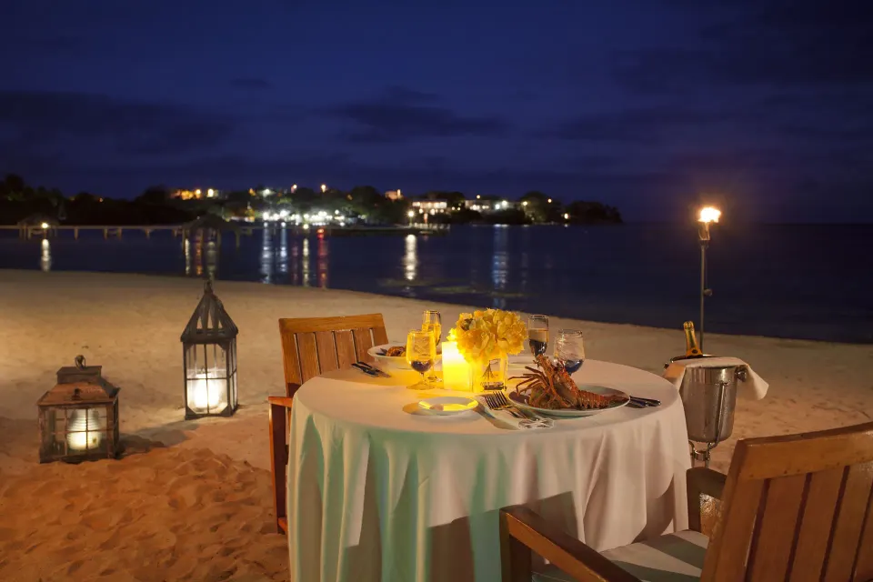 Candlelit dinner table on the sand by the water at Copamarina Beach Resort & Spa.