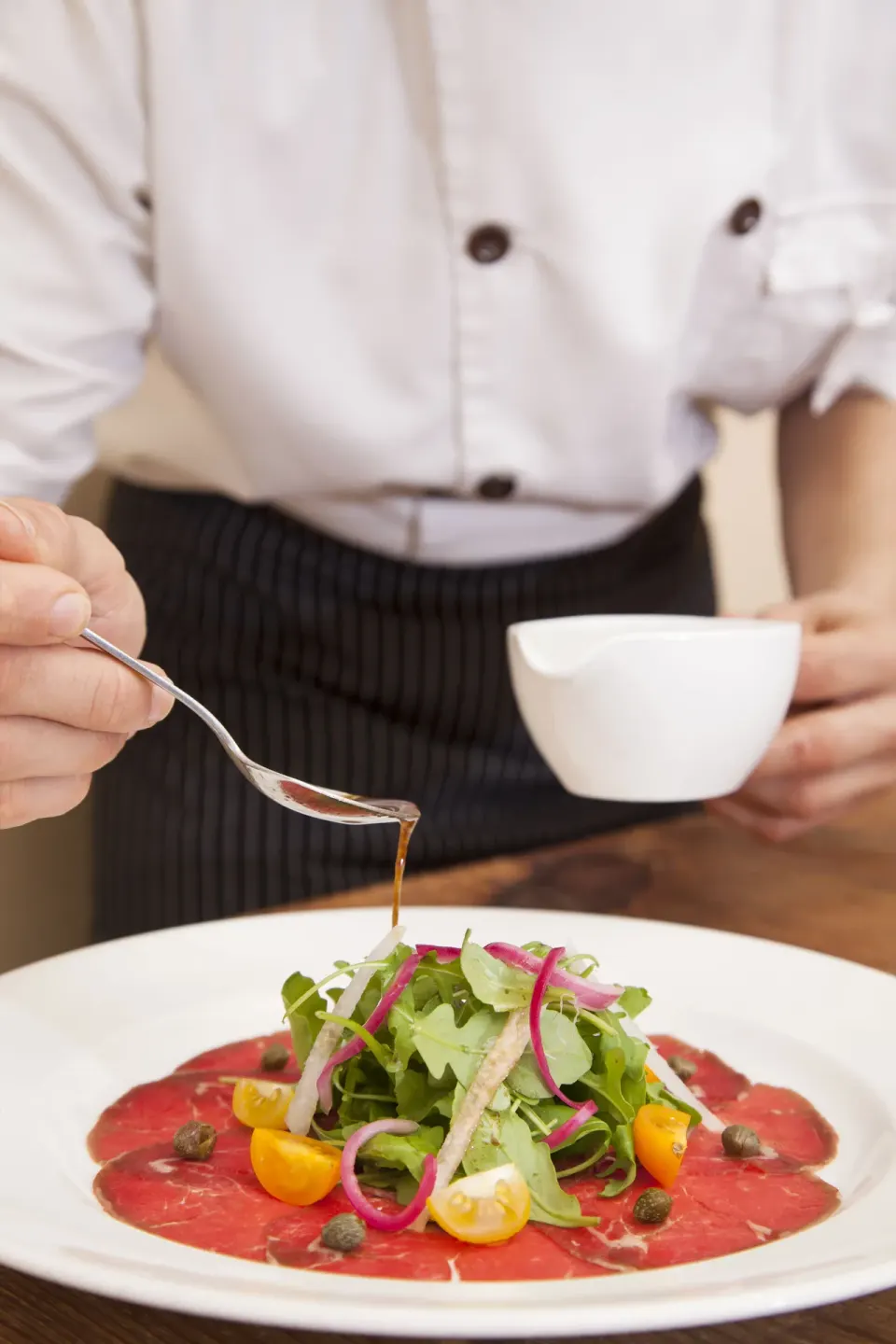 Chef drizzling dressing over a plated salad at Copamarina Beach Resort & Spa.
