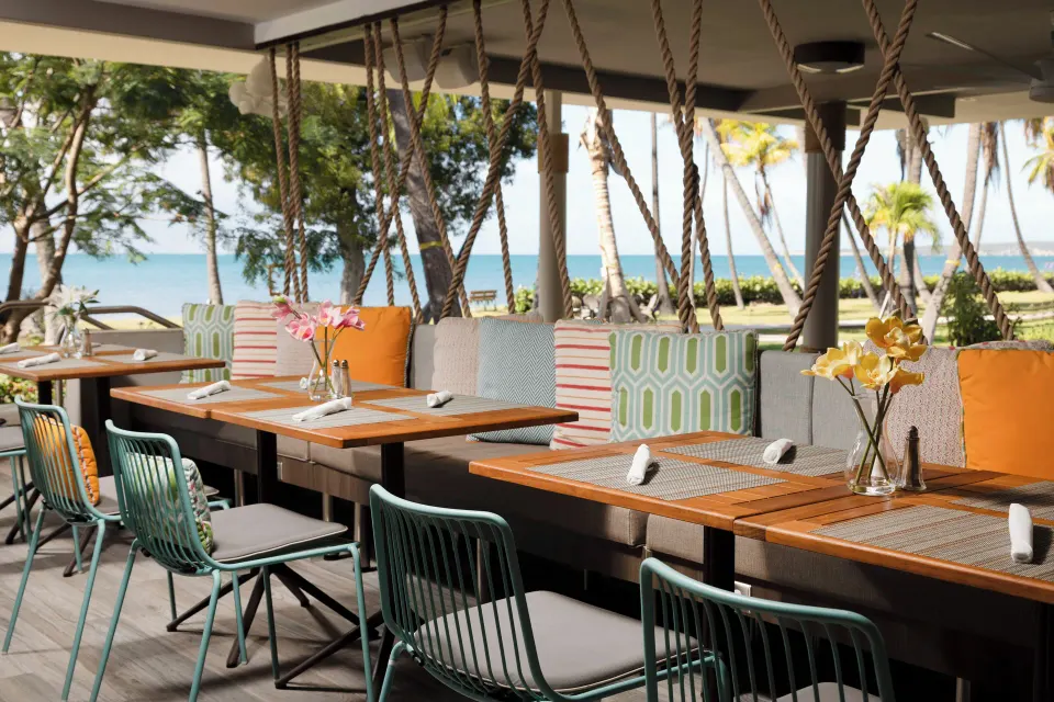 Outdoor dining tables with colorful seating and ocean views at Copamarina Beach Resort & Spa.