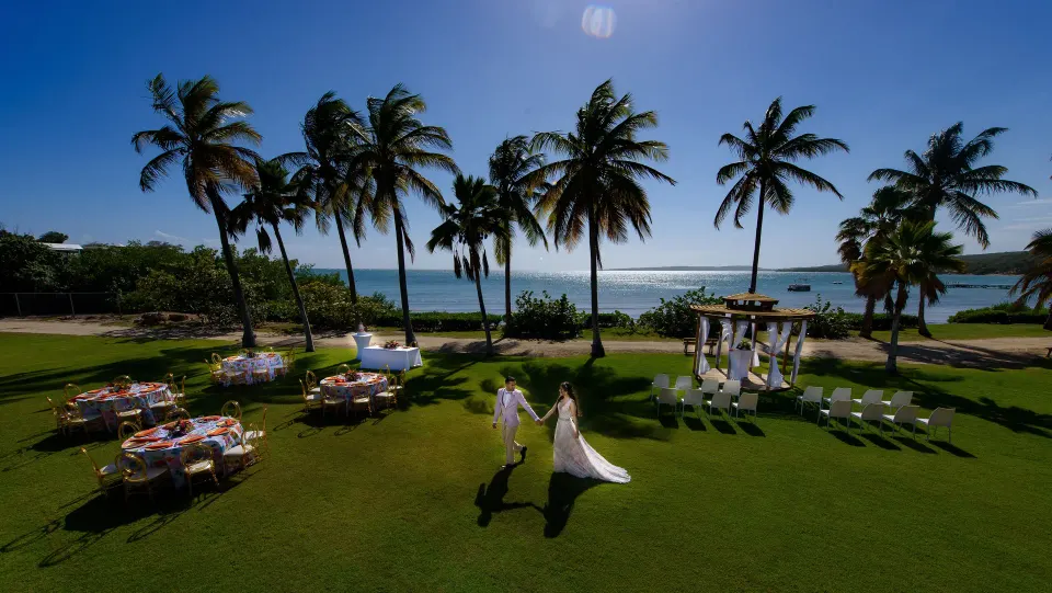 Bride and groom crossing the beachfront lawn at Copamarina Beach Resort & Spa.
