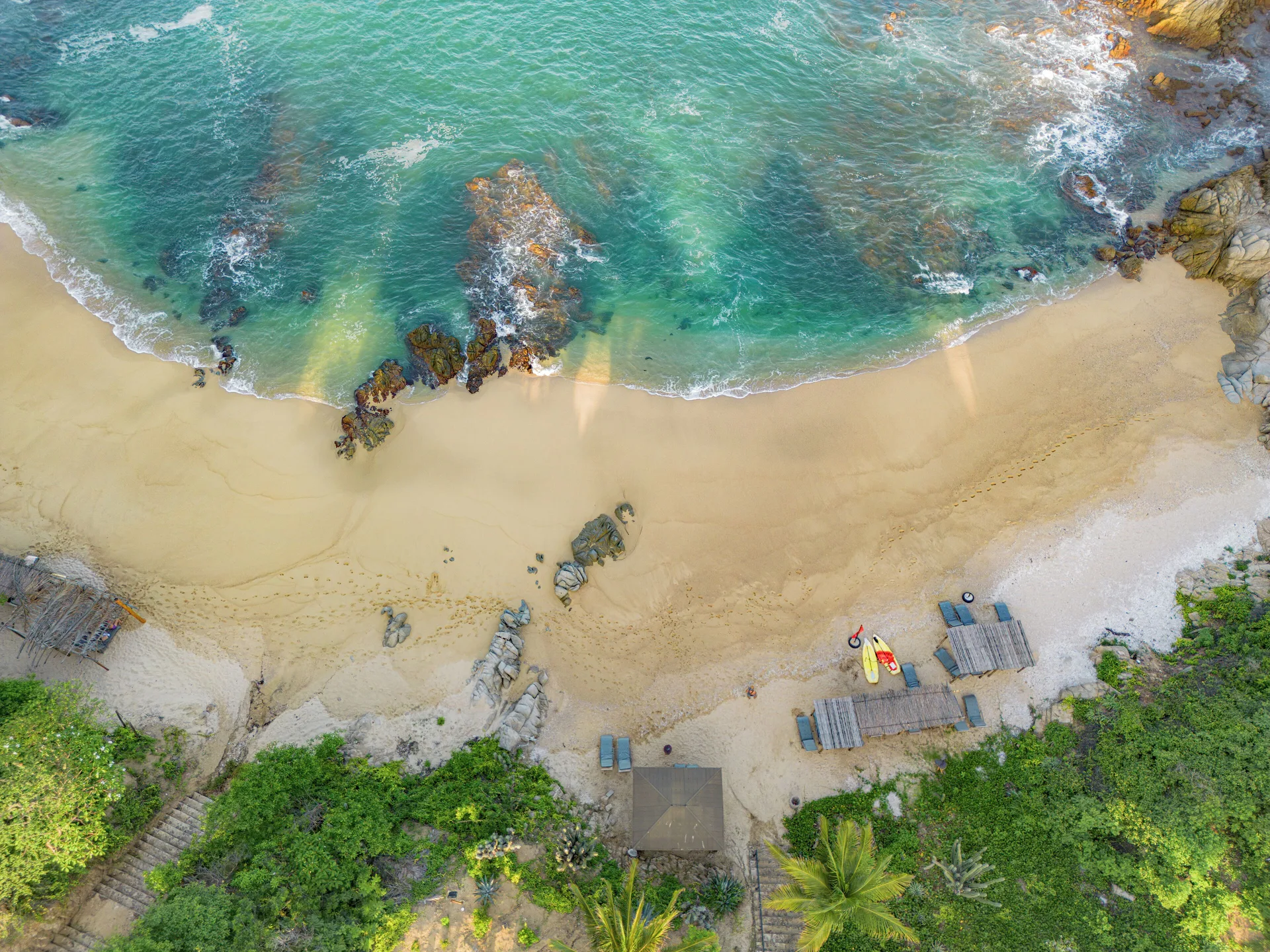 Aerial view of the sandy beach and turquoise water at Coral Blue Huatulco.