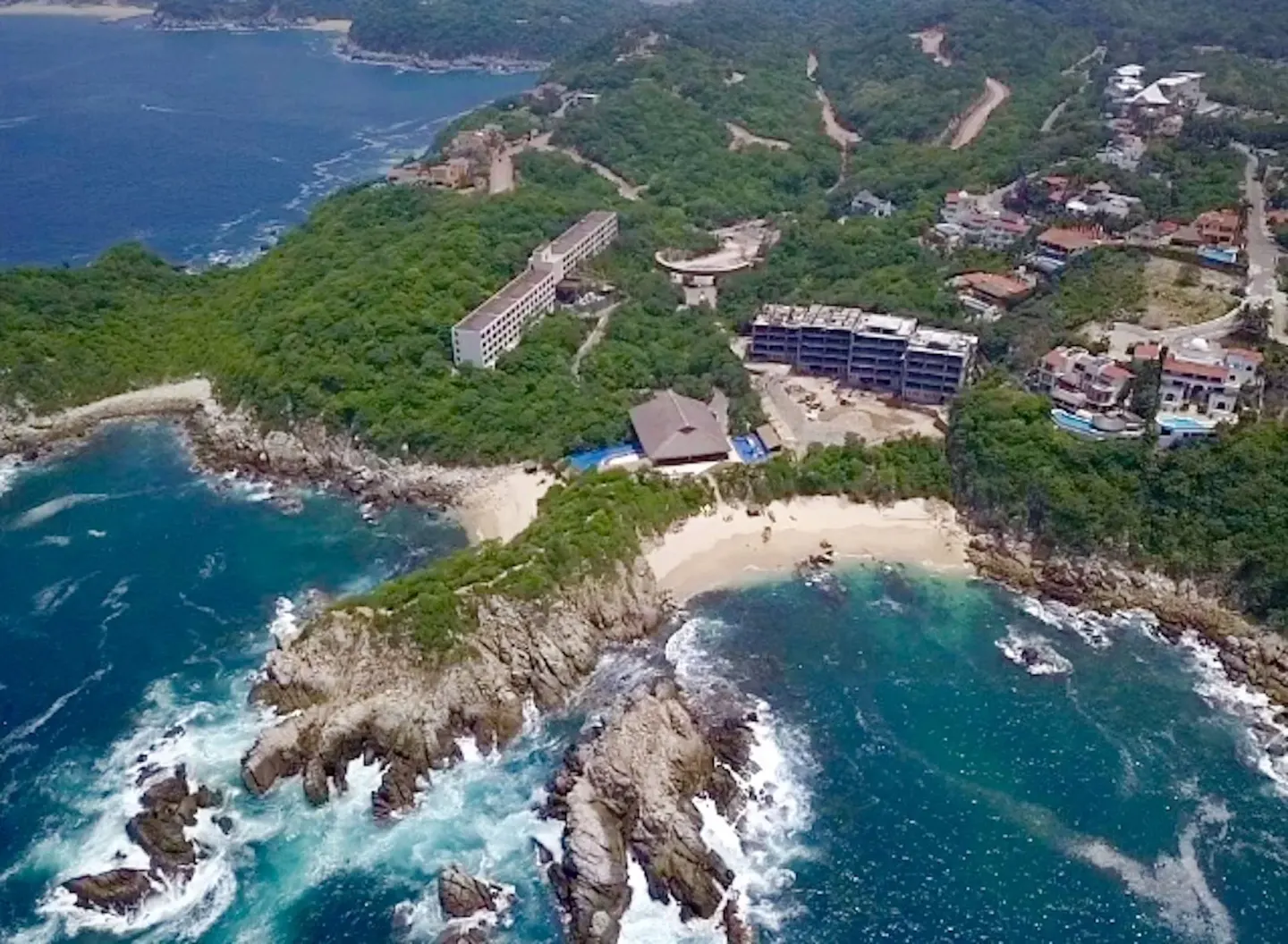 Aerial view of rocky coastline, beaches, and resort buildings at Coral Blue Huatulco.