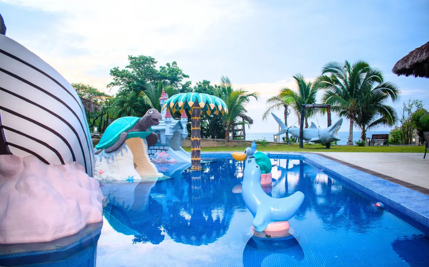 Children’s pool with animal slides and palm trees at Coral Blue Huatulco.