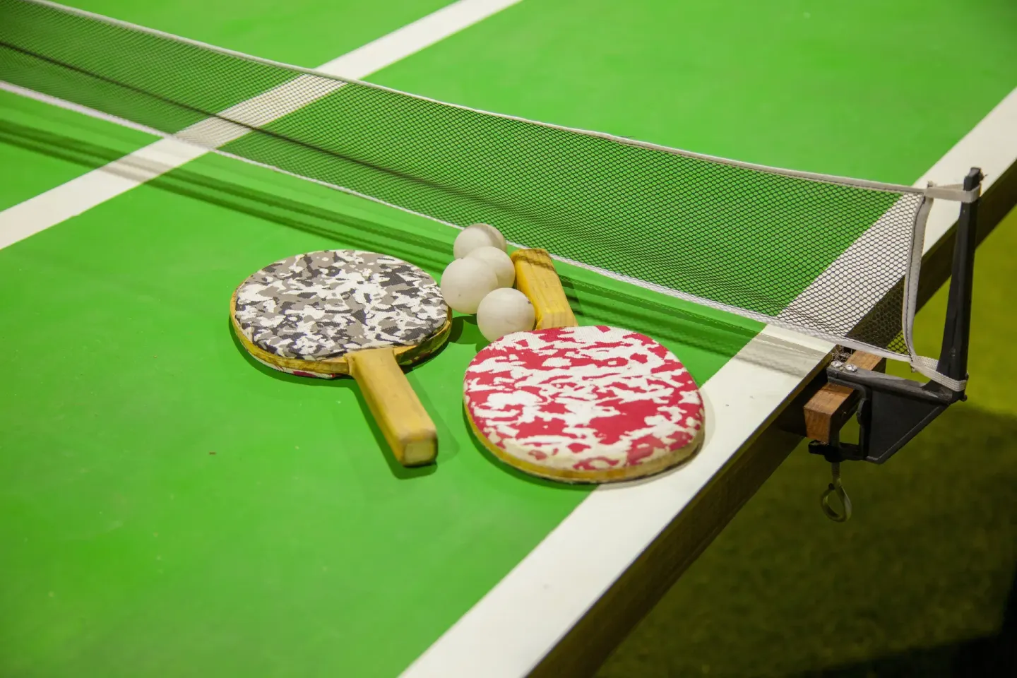 Ping pong paddles and balls on a green table at Coral Blue Huatulco.