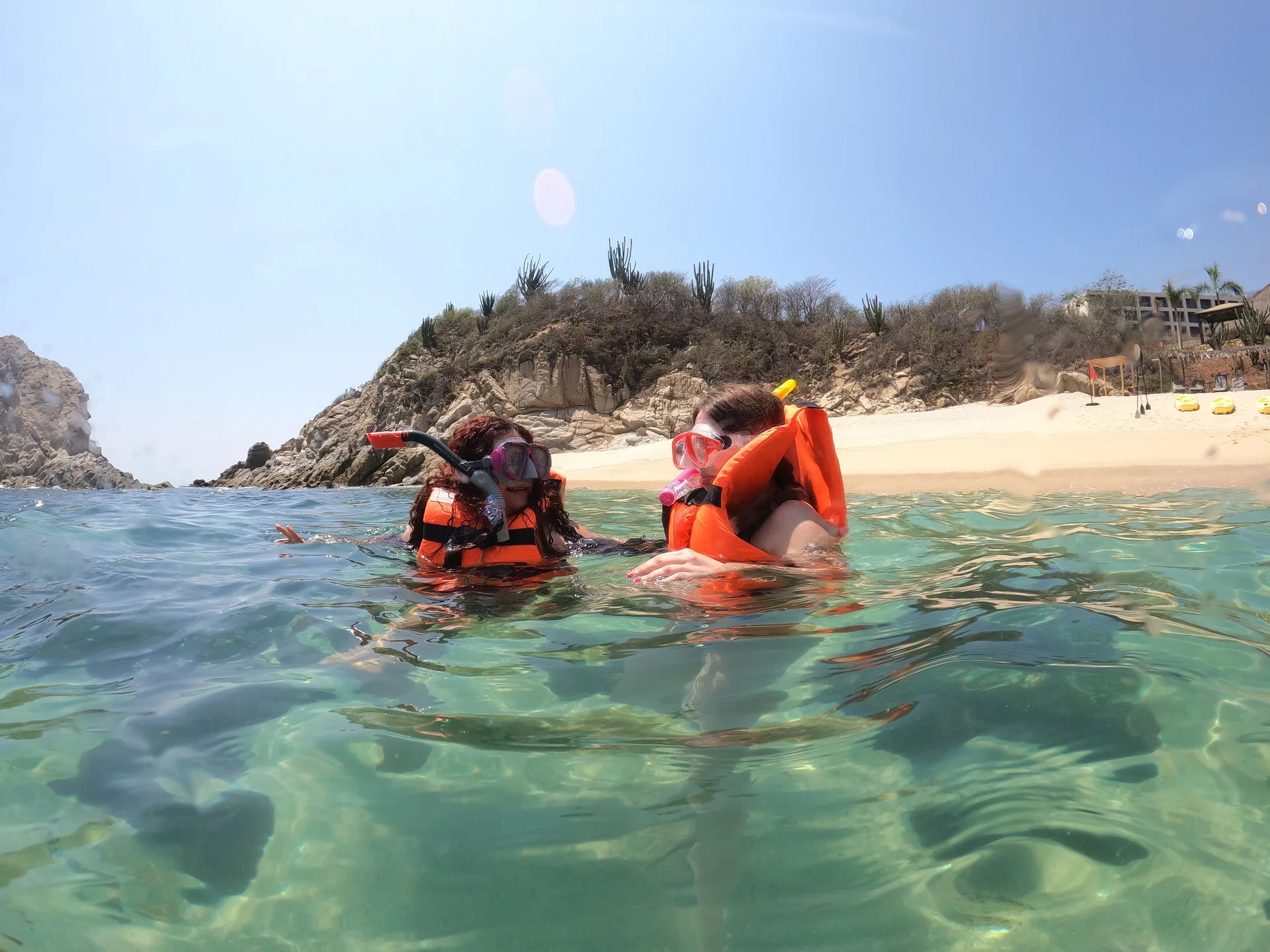 Two snorkelers floating in clear water near the beach at Coral Blue Huatulco.