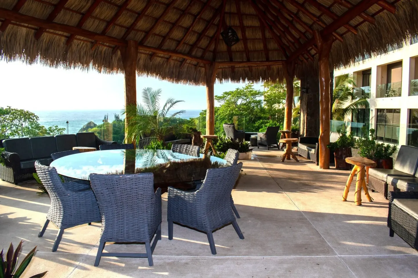 Thatched terrace with wicker seating and ocean views at Coral Blue Huatulco.