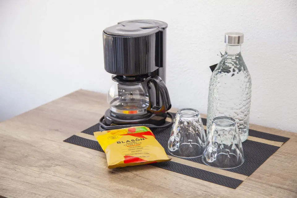 Coffee maker, cups, bottled water and coffee packets on a room counter at Coral Blue Huatulco.