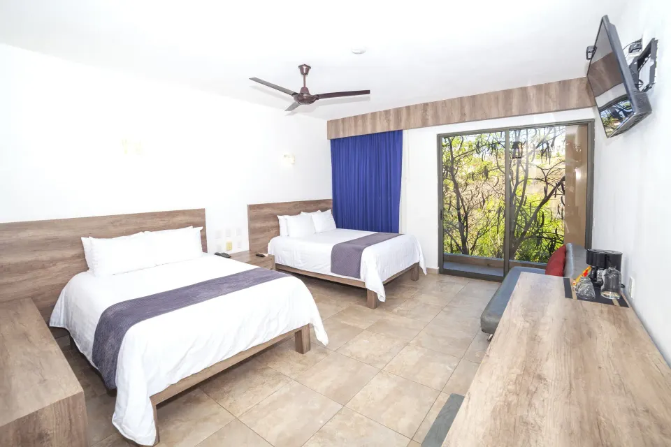 Deluxe Room with two beds, TV, desk and sliding glass doors at Coral Blue Huatulco.